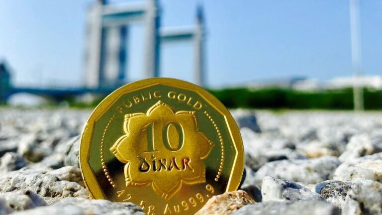 Koin emas Public Gold 10 Dinar di atas batu dengan latar langit cerah, ilustrasi pengaruh rupiah terhadap harga emas Antam