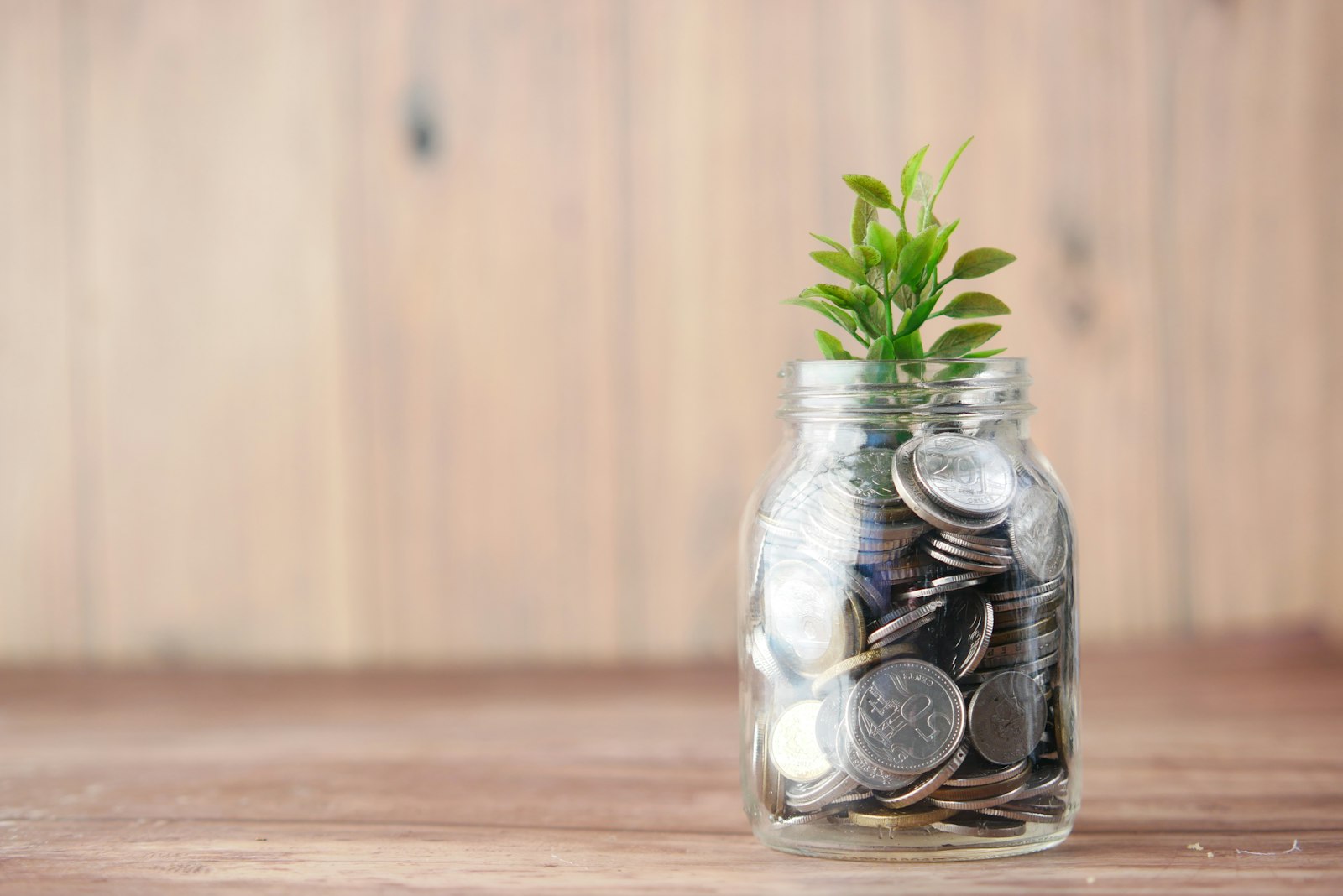 Toples kaca berisi koin dan tanaman melambangkan kenaikan tunjangan pensiun yang perlu mengimbangi inflasi